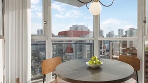 A dining area with a round table, two chairs, and a bowl of green apples.