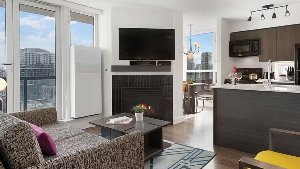 A modern living room with a fireplace, a flat-screen TV, and a dining area with a view.