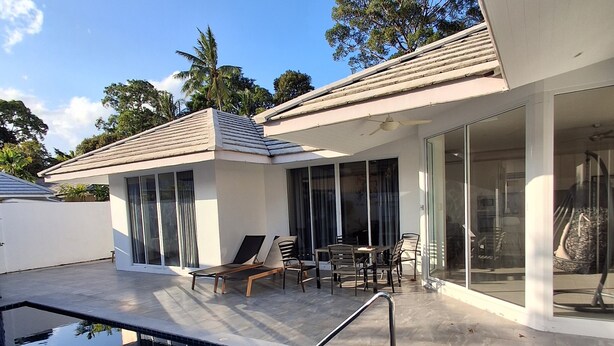 A modern outdoor pool area with a clear sky, a covered seating area, and a building with large windows. - 2-Bedroom Villa with 2 BTHR, Private Pool, Quiet Beach Just 2-Minute Walk Away (Koh SamuiProvince)