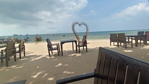 A beachside seating area with wooden chairs and tables, a heart-shaped decoration, and a view of the ocean. - 2-Bedroom Villa with 2 BTHR, Private Pool, Quiet Beach Just 2-Minute Walk Away (Koh SamuiProvince)