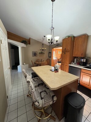 A kitchen with a central island, wooden cabinets, and a dining area with chairs. - Northern Oasis in the Warroad Estates (Warroad)