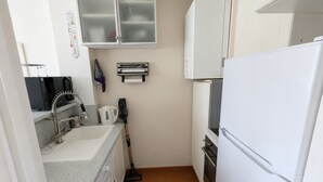 A compact kitchen with a sink, microwave, kettle, and a broom. - Seafront marina, a stone's throw from the beaches (Le Grau-du-Roi)