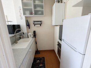 A compact kitchen with a sink, microwave, kettle, and a broom. - Seafront marina, a stone's throw from the beaches (Le Grau-du-Roi)