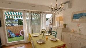 A dining area with a table set for four, a chandelier, and a view through a glass door to the outside. - Seafront marina, a stone's throw from the beaches (Le Grau-du-Roi)