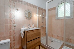 Een badkamer met een douche, een wastafel met spiegel en een toilet.