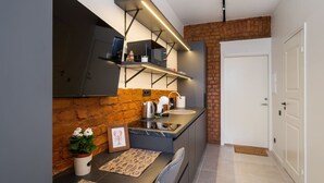 Une cuisine moderne avec un mur d’accent en briques, un four encastré et un plan de travail en acier inoxydable.