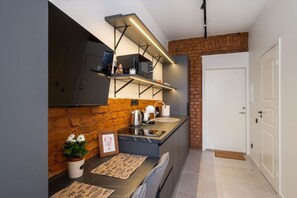 Una cocina moderna con pared de ladrillo decorativa, horno empotrado y encimera de acero inoxidable.