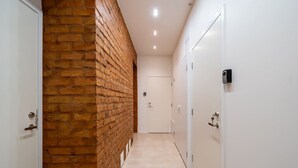 Ein Flur mit Backsteinwand, weißen Türen und Fliesenboden.