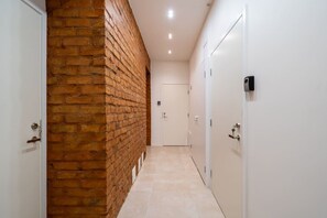 A hallway with a brick wall, white doors, and a tiled floor. - The Hidden Gem | Smart & Quiet Studio (Riga)