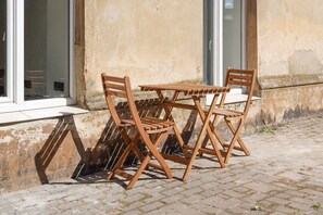 A wooden outdoor table and chairs set against a building with a textured wall and windows. - The Hidden Gem | Smart & Quiet Studio (Riga)