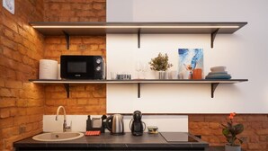 Eine Küche mit Backsteinwand, einer schwarzen Mikrowelle, einer Kaffeemaschine und einem Spülbecken.