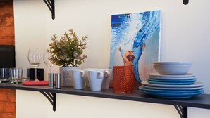 Eine Küchenarbeitsplatte mit einem Blumentopf, weißen Tassen, einer roten Tasse, einem Stapel blauer Teller und einem Bild einer Frau.