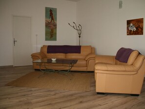 Ein Wohnzimmer mit einer Couch, einem Couchtisch, einem Teppich und zwei Bildern an der Wand.