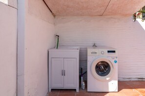 A small laundry area with a washing machine and a cabinet. - Golden Sunset - S'Archittu (S'Archittu)