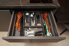 Eine Schublade mit Besteck, darunter Löffel, Gabeln und Messer, sowie eine Schere.