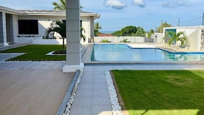 A modern house with a swimming pool, a covered patio, and a well-maintained lawn. - Zurano Villa – Your Spacious and Cosy Home Away from Home! (Dar es Salaam)