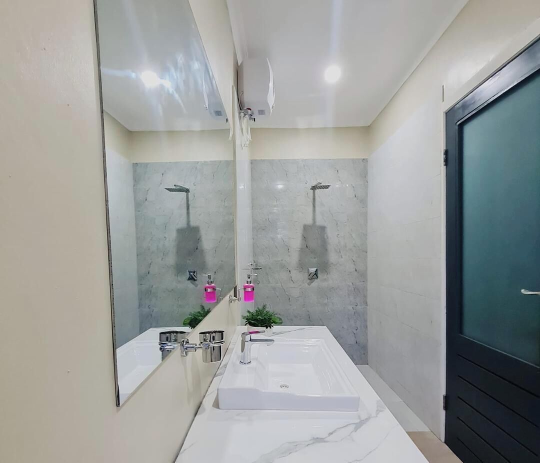 Une salle de bain moderne avec un grand miroir, deux lavabos, une douche et une porte en verre.