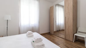 Een hotelkamer met een bed, een stoel, een spiegel en een kledingkast.