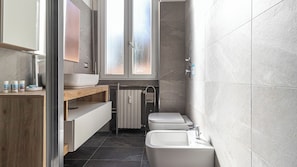 Een moderne badkamer met een badkuip, wastafel, spiegel en raam.