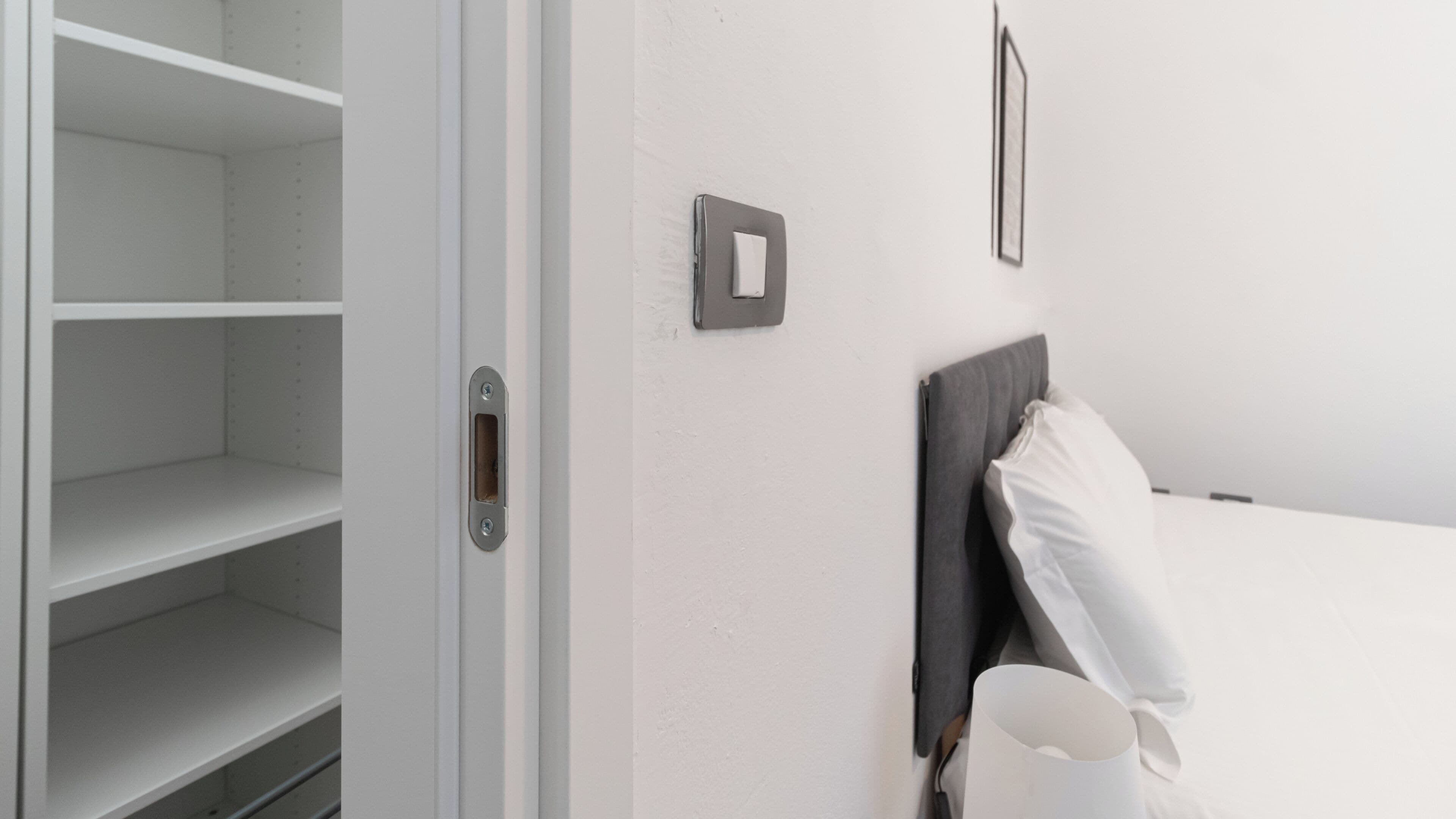 Ein Hotelzimmer mit einem Bett, einer Tür mit Griff und einem an der Wand befestigten Lichtschalter.