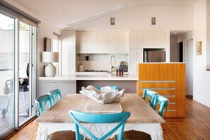Eine moderne Küche mit weißen Schränken, einem Holztisch und blauen Stühlen.