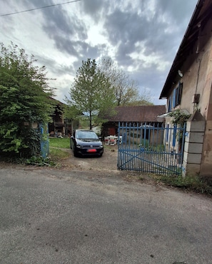 Ein gepflasterter Weg führt zu einem verschlossenen Eingang, darin ein geparktes Auto.