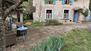 A rustic house with a garden, outdoor furniture, and a small table. - Ferme Berger-By & Le Nid, between the 2 lakes (Pressins)