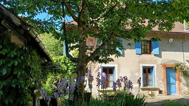 A two-story house with a garden, a blue gate, and a tree in the foreground. - Ferme Berger-By & Le Nid, between the 2 lakes (Pressins)