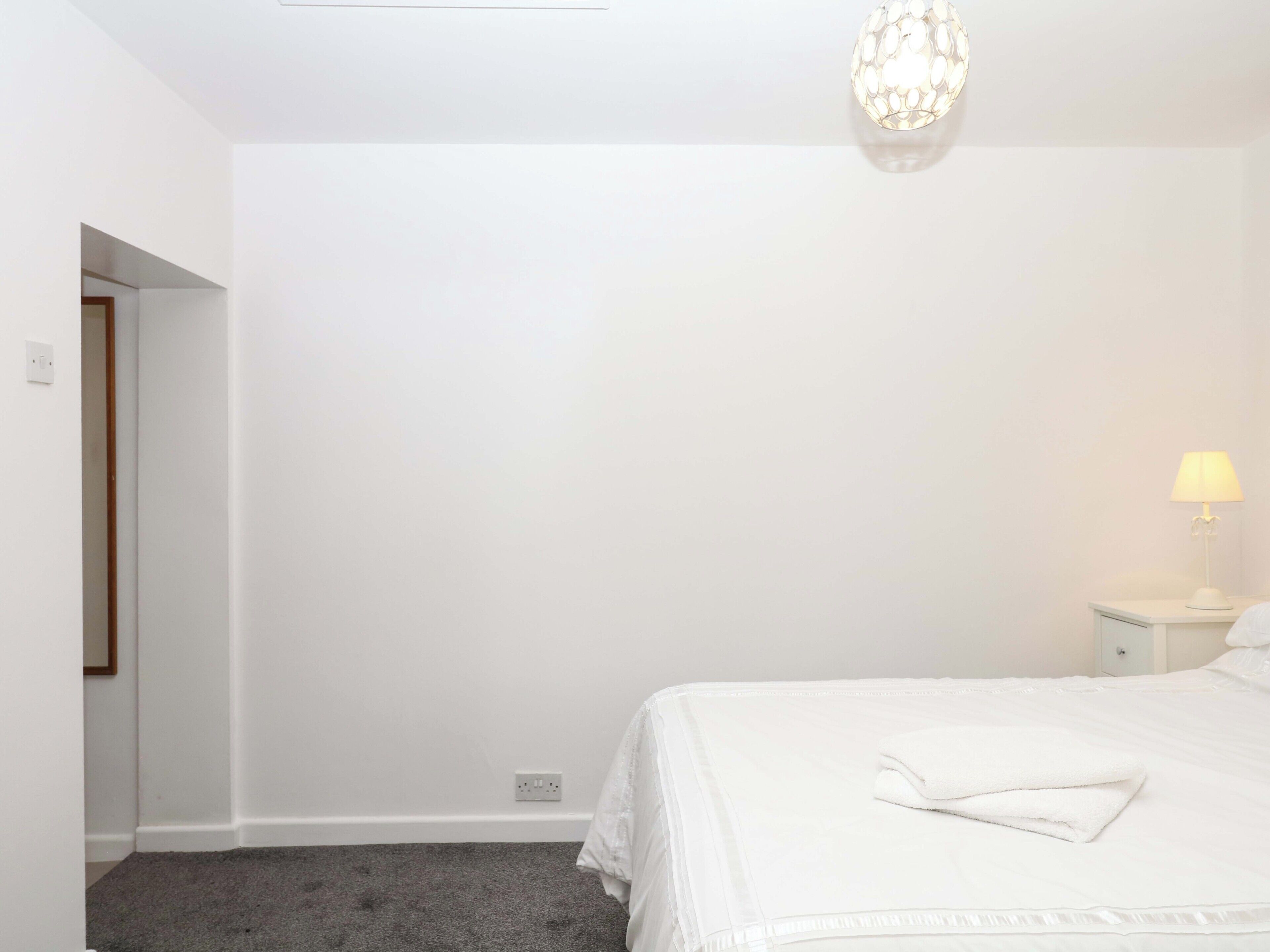 A bedroom with a bed, a nightstand, a lamp, and a chandelier.