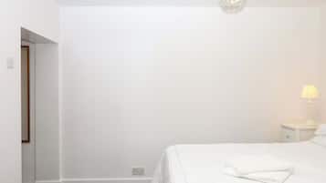 A bedroom with a bed, a nightstand, a lamp, and a chandelier.