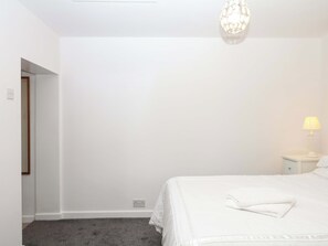 A bedroom with a bed, a nightstand, a lamp, and a chandelier.