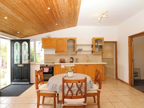 Una cocina con armarios de madera, una estufa y una mesa de comedor con sillas.