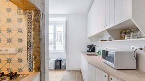 Une cuisine moderne avec des meubles blancs, un four à micro-ondes et une machine à café.
