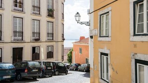 Une rue bordée de voitures garées, un immeuble doté de balcons et un lampadaire.