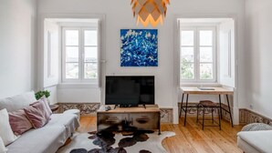 Un salon comprenant un téléviseur, un canapé, un bureau et des œuvres d’art.