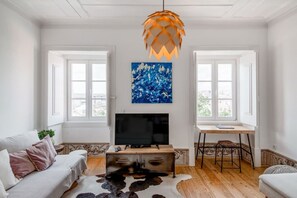A living room with a TV, sofa, desk, and artwork. - Stunning Views | Authentic Lisbon Living (Lisbon)