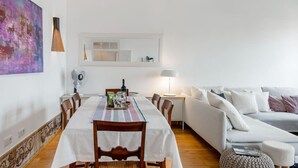 Un coin repas avec une table dressée pour deux personnes, un canapé et une lampe.