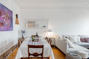 A dining area with a table set for two, a sofa, and a lamp. - Stunning Views | Authentic Lisbon Living (Lisbon)