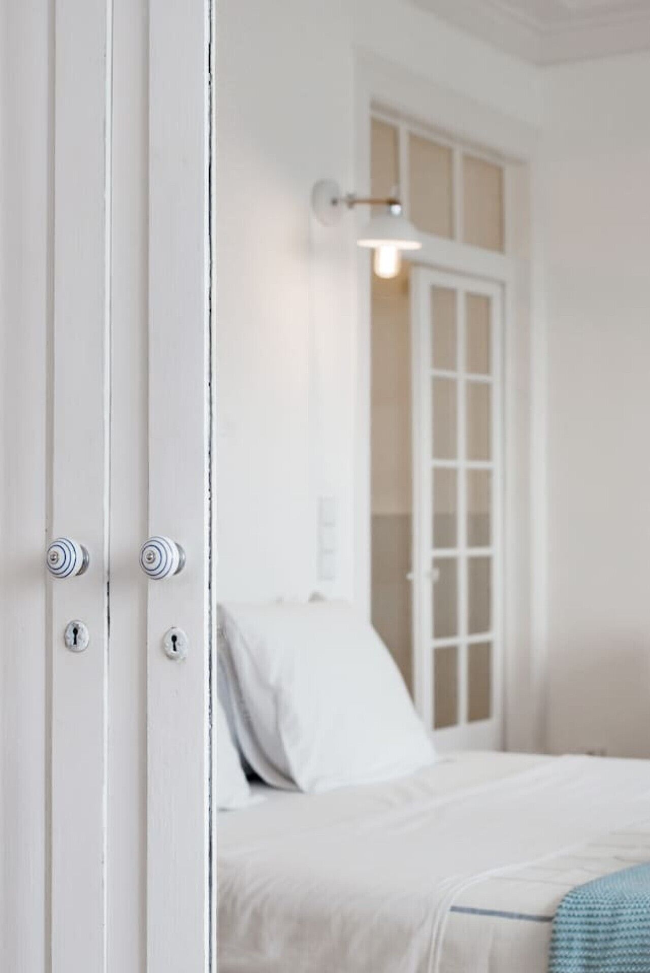 A room with a bed, a door with a keyhole, and a light fixture.