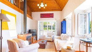 A spacious living room with a fireplace, white sofas, a television, and a large window. - Country Escape, Pool, BBQ, Pizza Oven & Games Barn (Pontével)