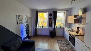 Ein kompakter Wohnbereich mit Sofa, Essplatz, Küche und Heizkörper.