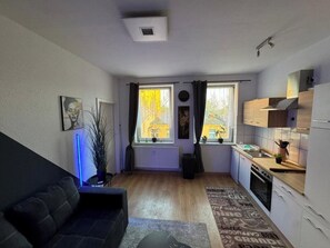 Ein kompakter Wohnbereich mit Sofa, Essplatz, Küche und Heizkörper.