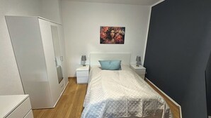 Ein Schlafzimmer mit einem Bett, Nachttischen, einem Kleiderschrank und einem Bild an der Wand.