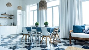 A modern kitchen with white cabinets, a black and white checkered floor, and a dining area with a table and chairs. - Floating Over the Sado | Arrábida, Beaches & Town (Setúbal)