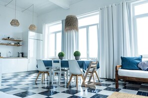 Eine moderne Küche mit weißen Schränken, einem schwarz-weißen Schachbrettboden und einem Essbereich mit Tisch und Stühlen.