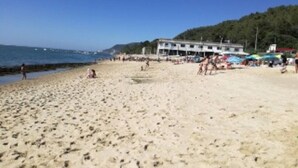 A beach with a building in the background. - Modern Coastal Ocean Breeze Studio | Beach & Town (Setúbal)
