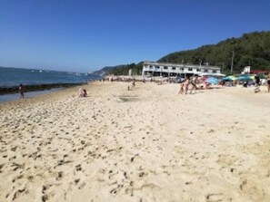 Ein Strand mit einem Gebäude im Hintergrund.