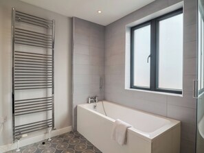 A modern bathroom with a bathtub, a glass shower enclosure, and a window. - Wagtail Cottage (Lyme Regis)