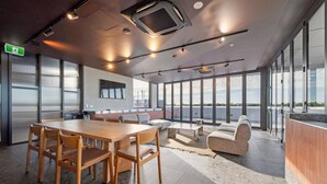 A modern conference room with a large table, chairs, a sofa, and a view through large windows. - Oceanique Penthouse in Leighton Beach (North Fremantle)