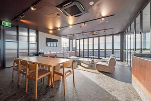 Ein moderner Konferenzraum mit einem großen Tisch, Stühlen, einer Couch und Blick durch große Fenster.